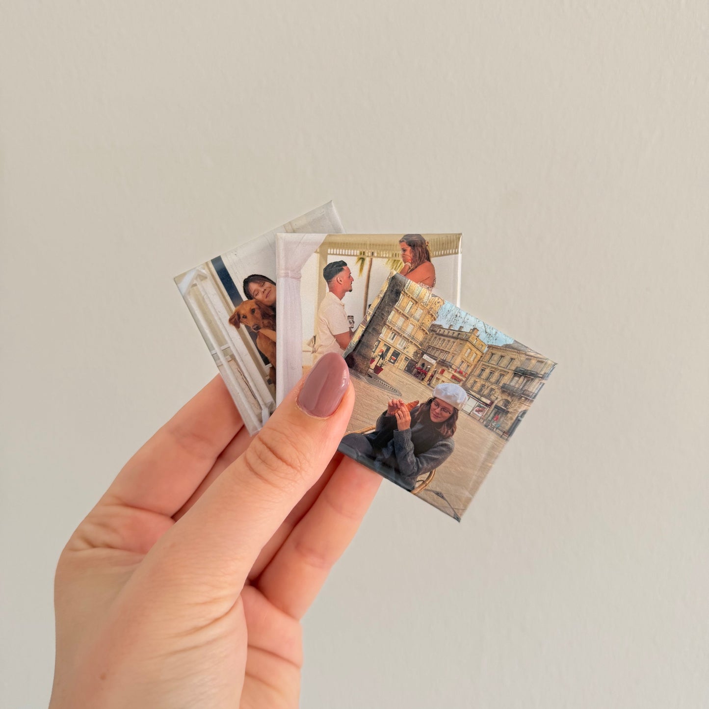 mão a segurar vários ímanes personalizados com fotografias, formato quadrado