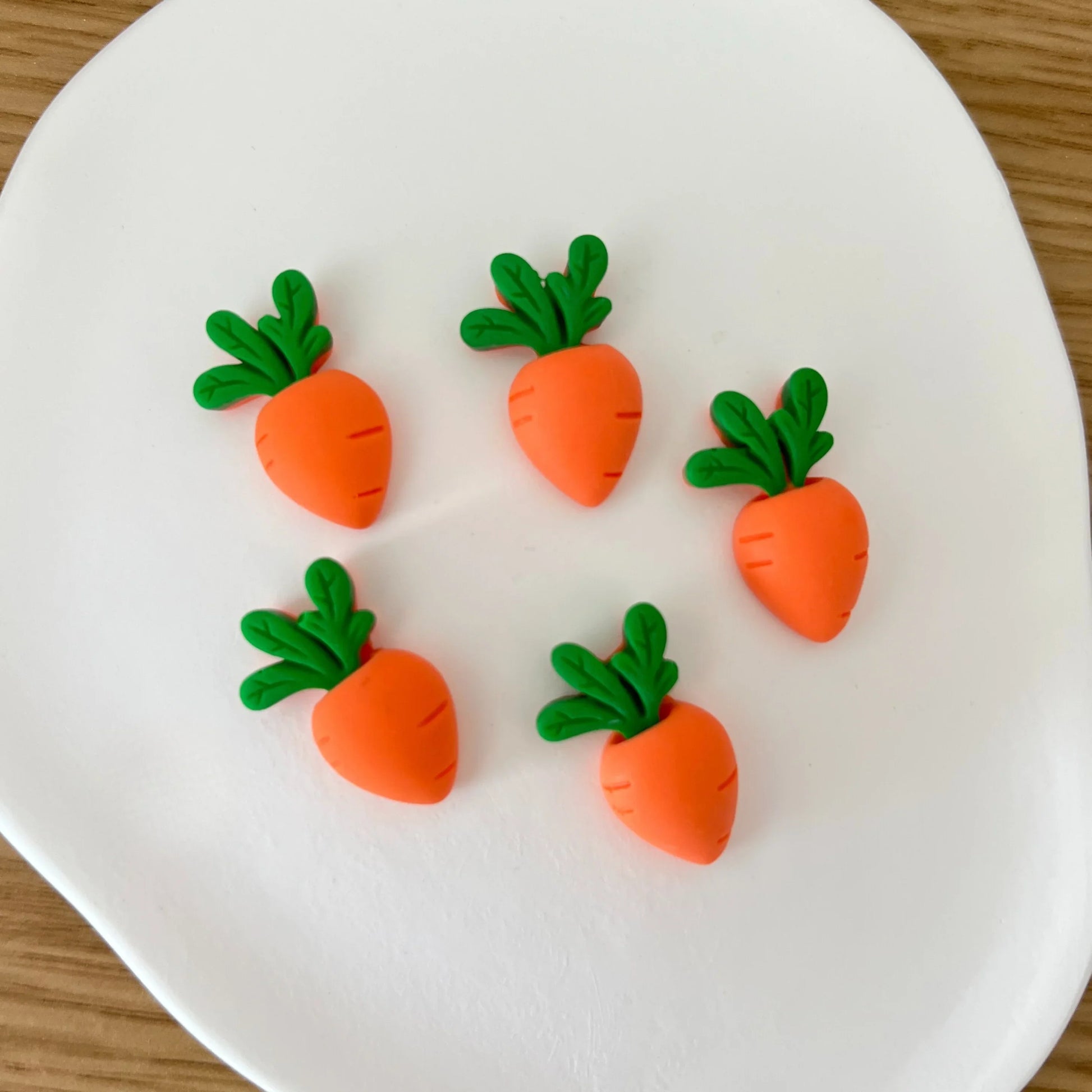 Conjunto de mini ímanes decorativos em forma de cenoura sobre prato branco
